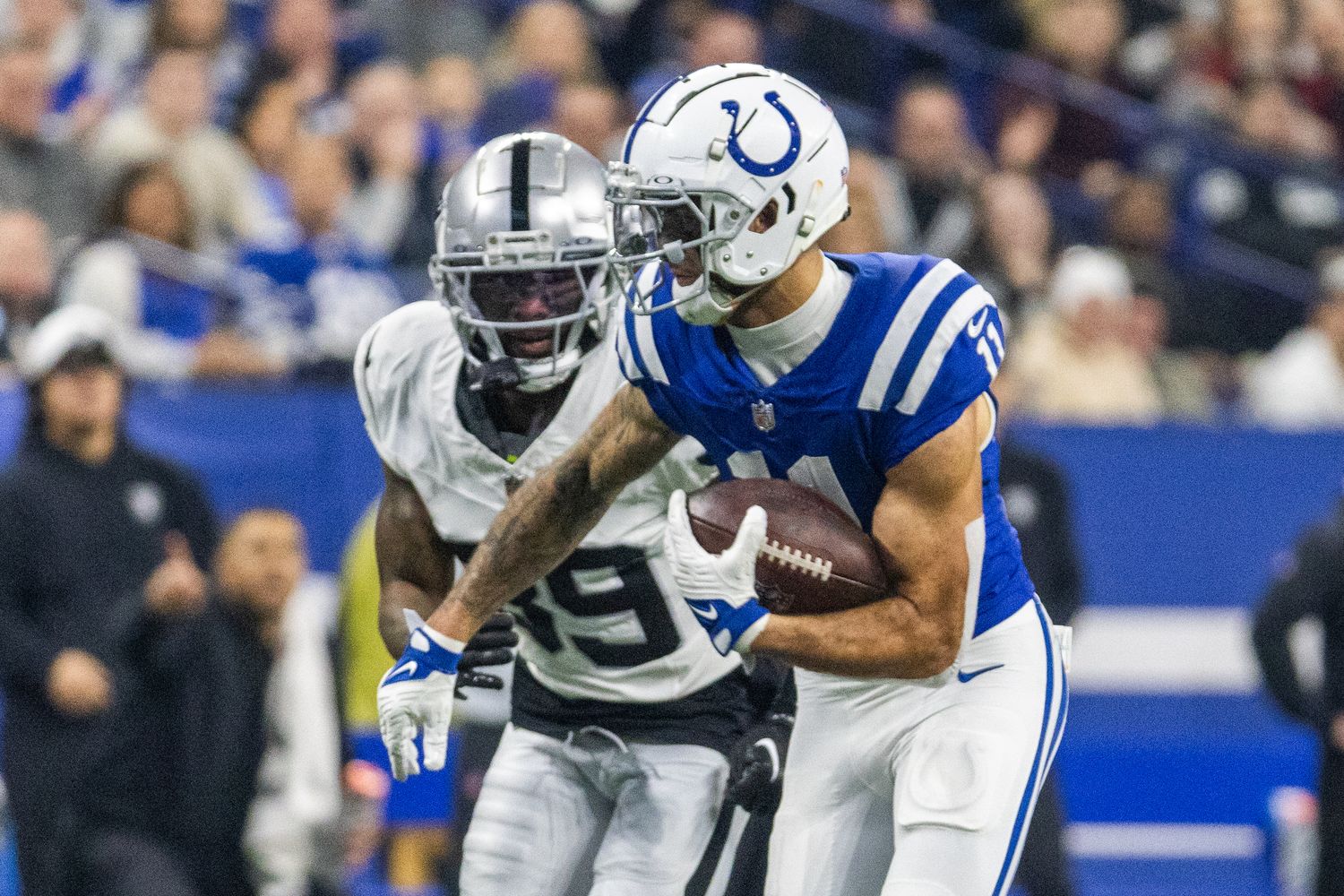 Dec 31, 2023; Indianapolis, Indiana, USA; Indianapolis Colts wide receiver Michael Pittman Jr. (11) runs with the ball after a catch while Las Vegas Raiders cornerback Nate Hobbs (39) defends in the second half at Lucas Oil Stadium.